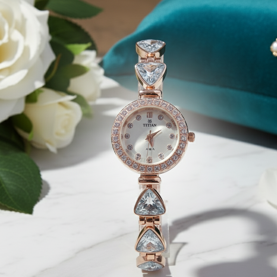 Rose gold watch with gemstones on a white surface with flowers and a teal object in the background