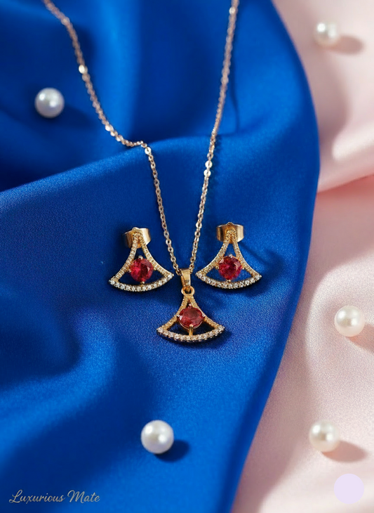 Gold jewelry set with red gemstones on a blue fabric background