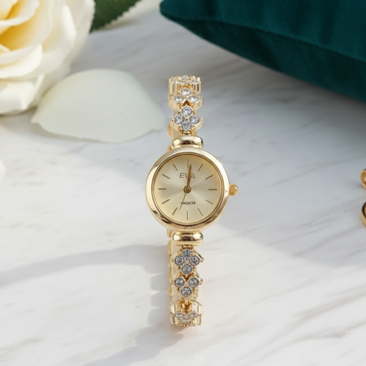 Gold wristwatch with decorative band on a white surface with flowers