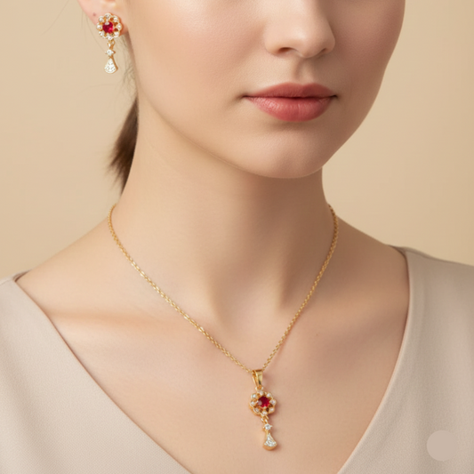 Gold necklace with a red gemstone pendant worn by a model against a beige background